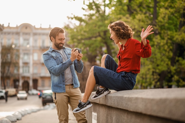 Stylish couple in love sitting in street on romantic trip, taking photo