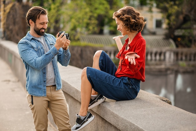 Stylish couple in love sitting in street on romantic trip, taking photo