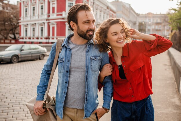 Stylish couple in love walking embracing in street on romantic trip