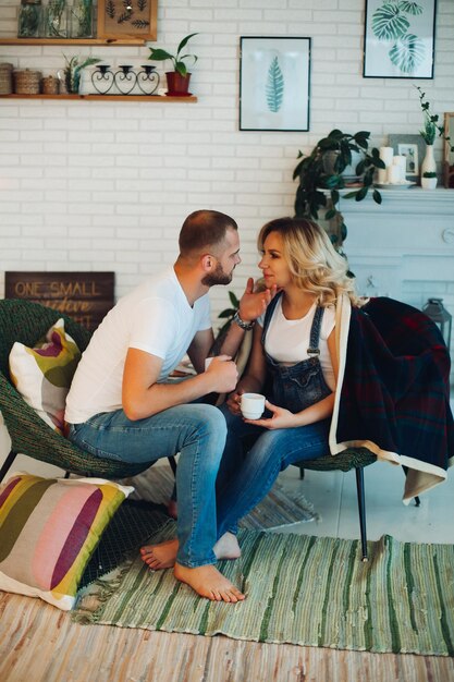 Stylish couple sitting on bad and embracing stomach