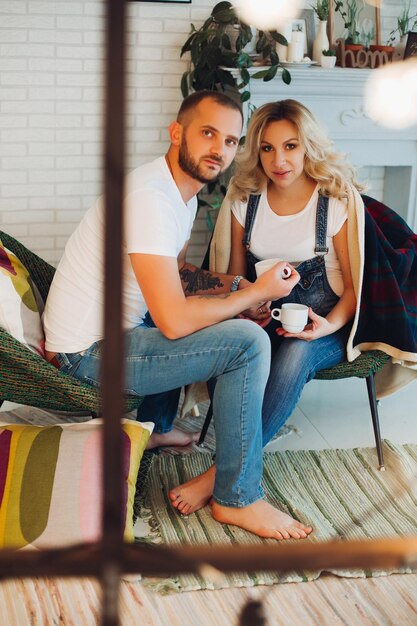 Stylish couple sitting on bad and embracing stomach