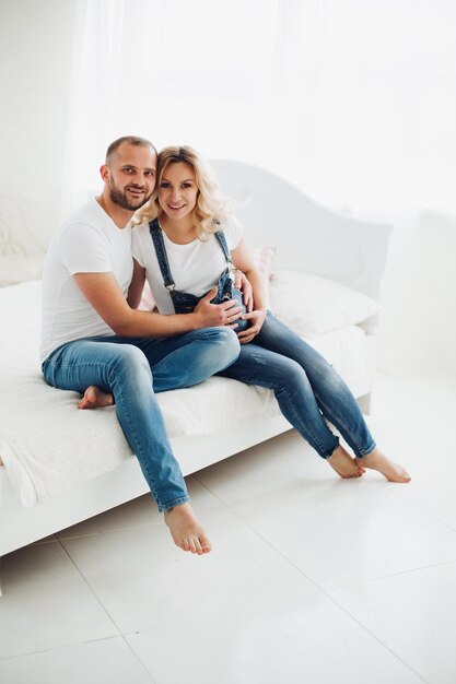 Stylish couple sitting on bad and embracing stomach