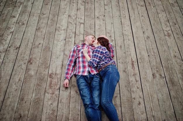 Stylish couple wear on checkered shirt in love together lie on the boards