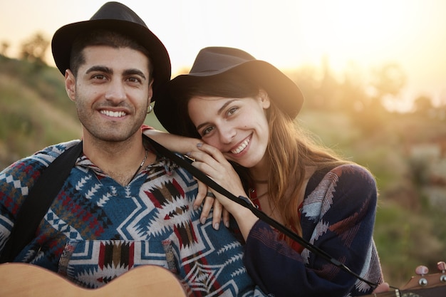 Free photo stylish couple with guitar on field