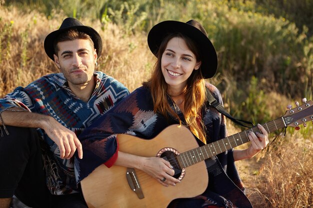 Stylish couple with guitar on field