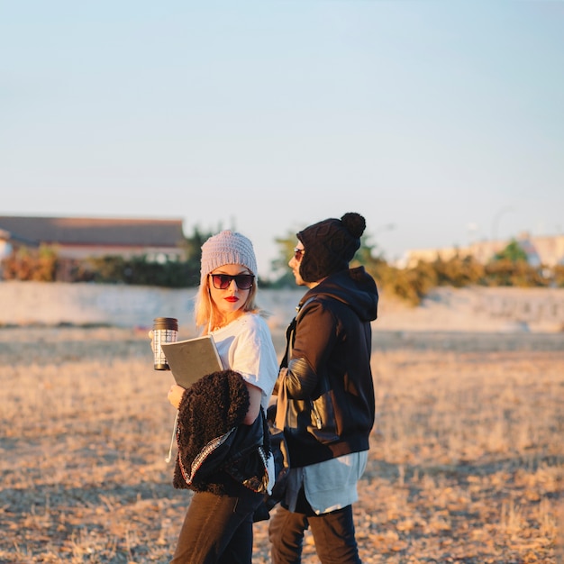 Stylish couple with thermoses walking together