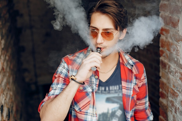 Free photo stylish and elegant man in a city with vape