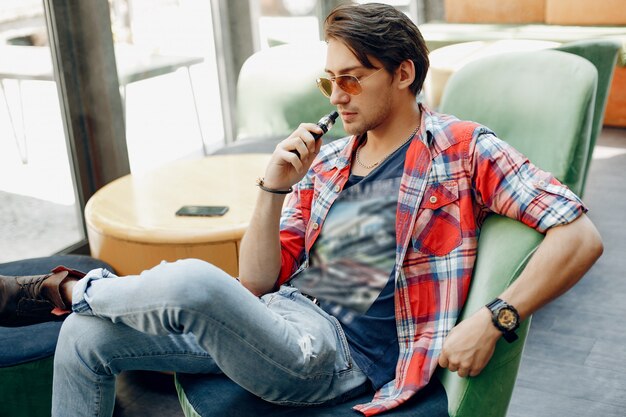 Stylish and elegant man sitting in a cafe with vape