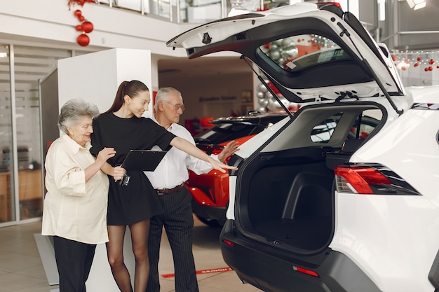 Foto gratuita vecchie coppie alla moda ed elegante in un salone dell'automobile