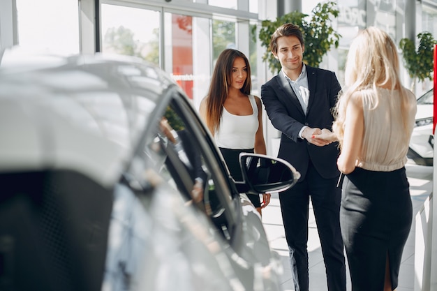 Foto gratuita persone eleganti e alla moda in un salone di auto