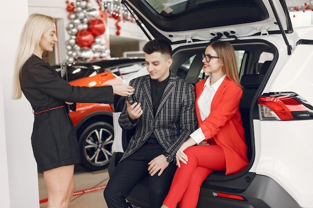 Foto gratuita persone eleganti e alla moda in un salone d'auto