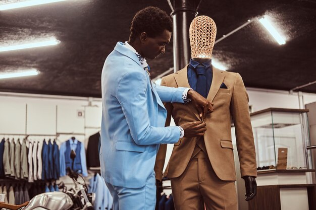 세련되고 우아하게 옷을 입은 아프리카계 미국인 남성이 클래식 남성복 매장에서 일하고 있습니다.