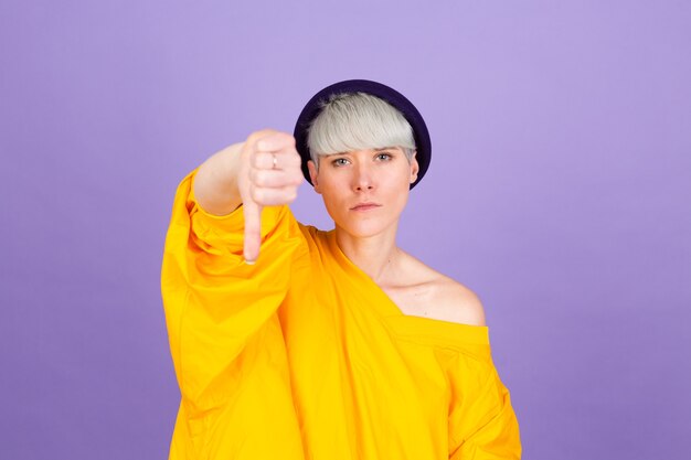 Stylish european woman on purple wall. looking unhappy and angry showing rejection and negative with thumbs down gesture. Bad expression