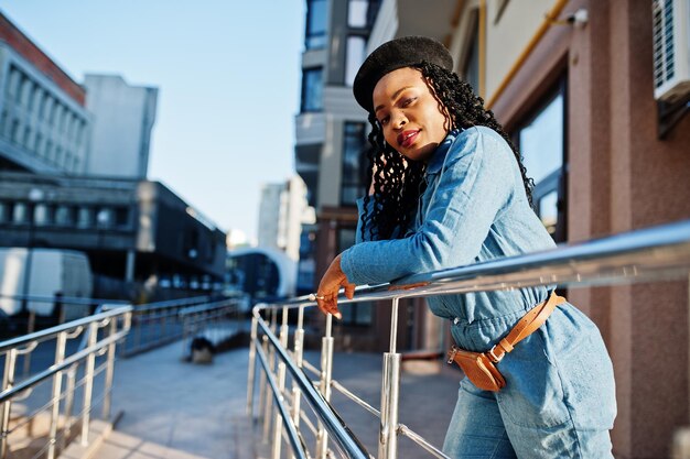 청바지를 입은 세련된 아프리카계 미국인 여성과 현대적인 건물에 대한 검은 베레모
