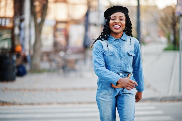 Stylish fashionable african american women in jeans wear and black beret walking on pedestrian traffic