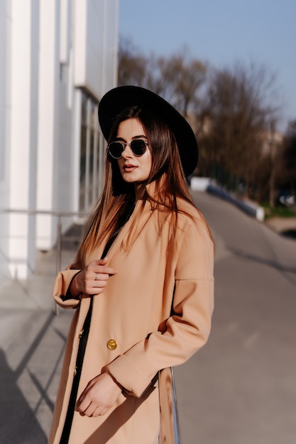 Free photo stylish fashionable woman in black hat standing and posing outdoors.