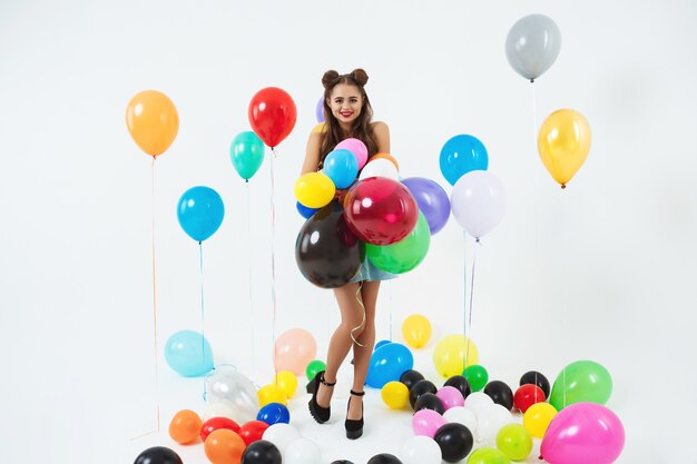 Stylish female hipster posing with big balloons on white