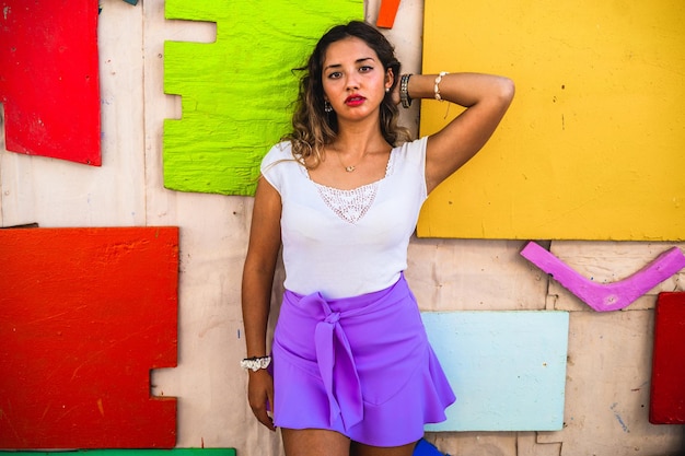 Free photo stylish female wearing a purple skirt paired with a white shirt and posing against an old building