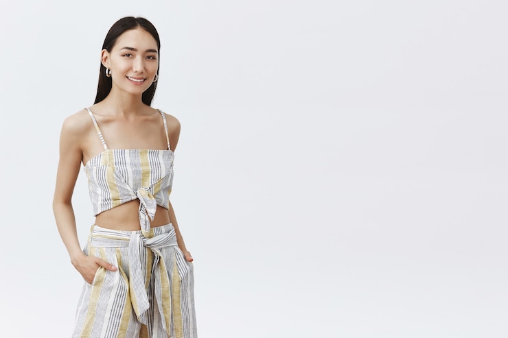 無料Photo 白い壁に生意気に見えるスタイリッシュなフェミニンな若いアジアの女性