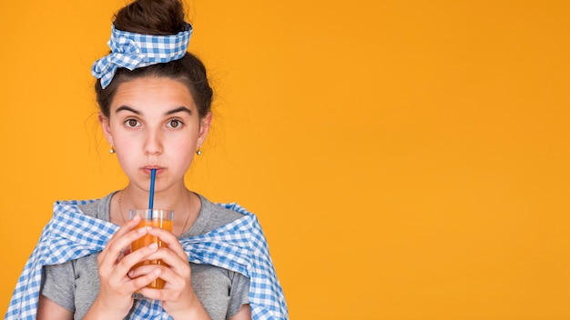 Foto gratuita ragazza alla moda che beve il succo di arancia con lo spazio della copia