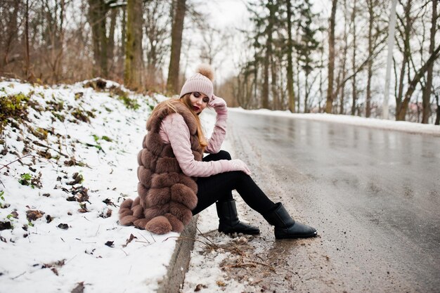 앉아있는 국경 ofroad에 겨울 날 모피 코트와 모자를 쓴 세련된 소녀