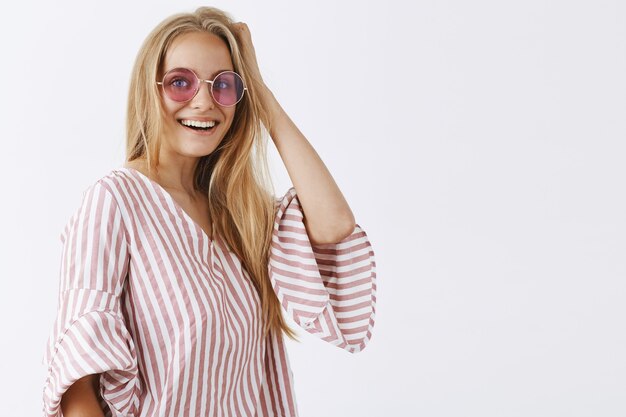 stylish girl posing against the white wall with sunglasses