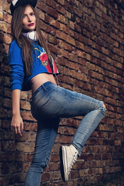 Stylish girl posing near a brick wall