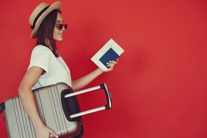 Stylish girl posing with travel equipment on a red wall