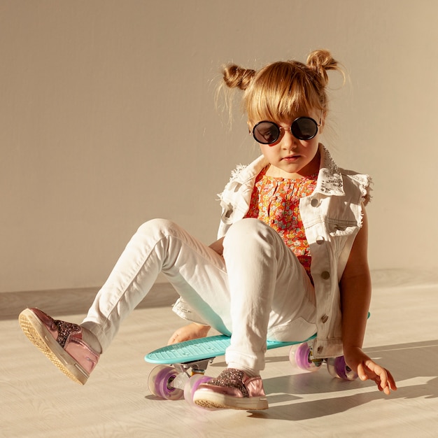 Stylish girl sitting on skateboard