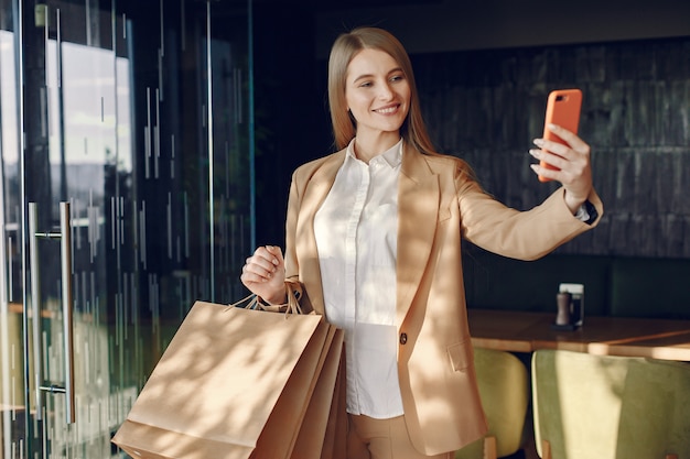 Stylish girl standing in a cafe with shopping bags