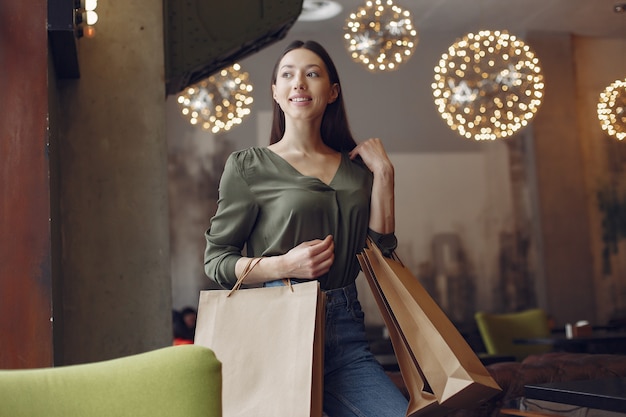 Stylish girl standing in a cafe with shopping bags