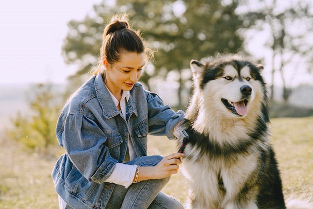 Stylish girl in a sunny field with a dog