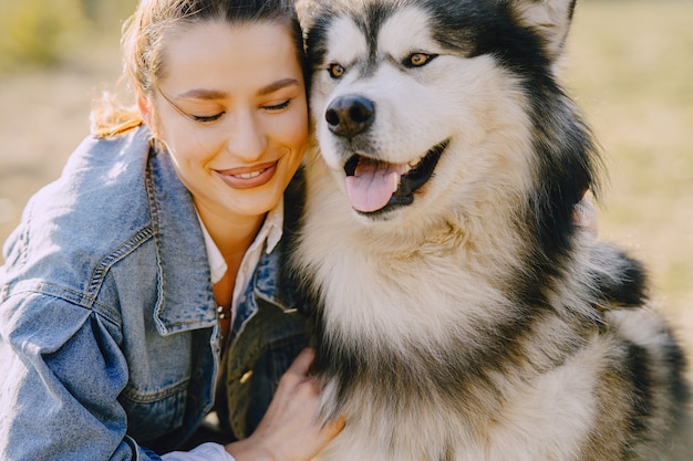 Stylish girl in a sunny field with a dog