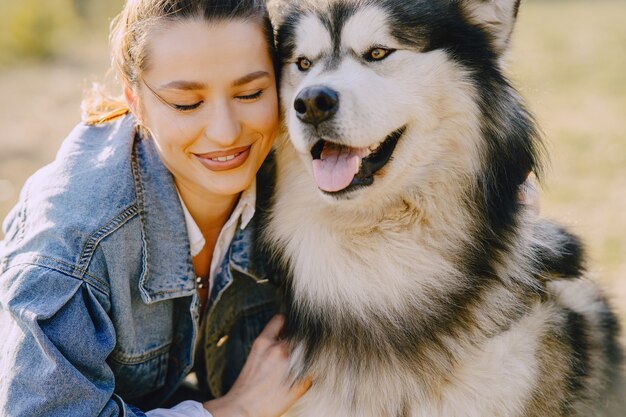 Stylish girl in a sunny field with a dog