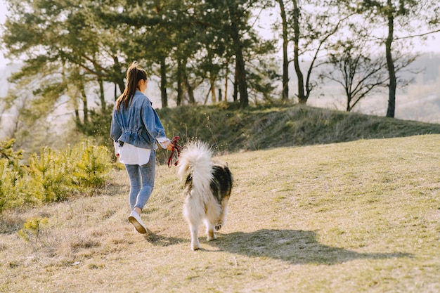 Stylish girl in a sunny field with a dog