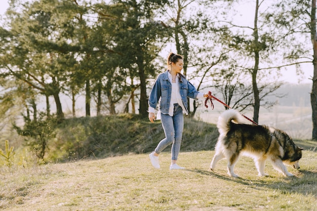 Stylish girl in a sunny field with a dog