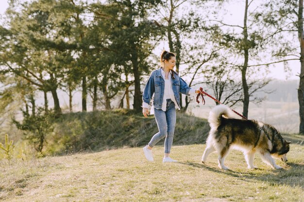 Стильная девушка в солнечном поле с собакой