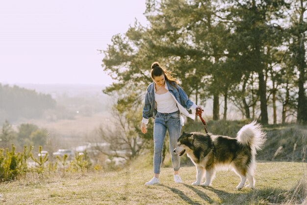 Stylish girl in a sunny field with a dog