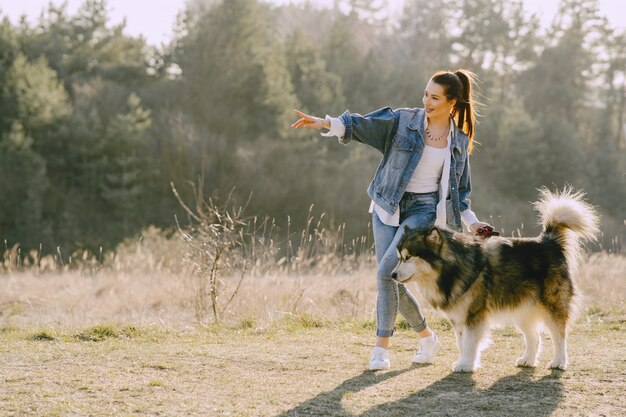 Stylish girl in a sunny field with a dog