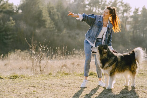 Стильная девушка в солнечном поле с собакой