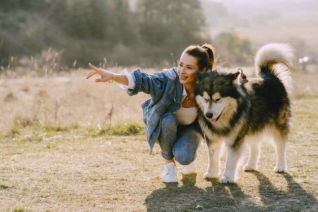 Stylish girl in a sunny field with a dog