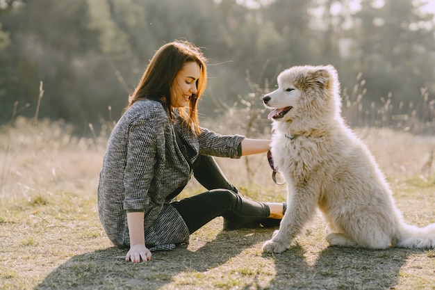 Stylish girl in a sunny field with a dog