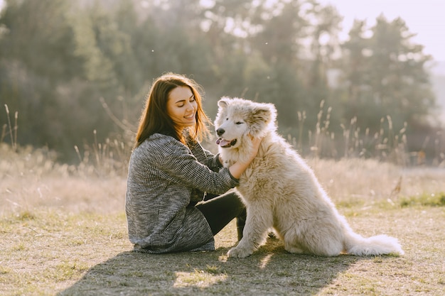 Stylish girl in a sunny field with a dog