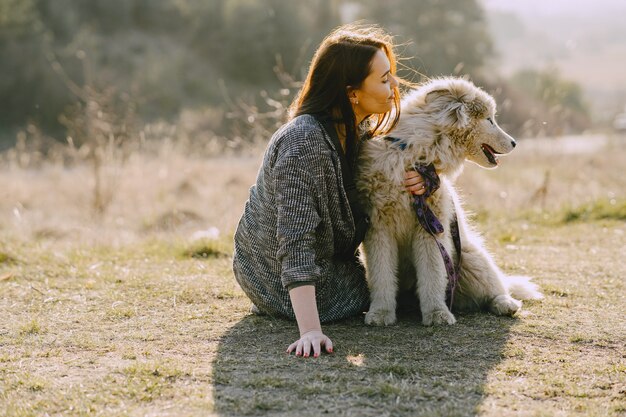 犬と日当たりの良いフィールドでスタイリッシュな女の子