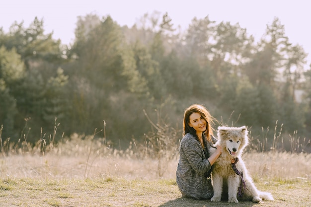 Stylish girl in a sunny field with a dog