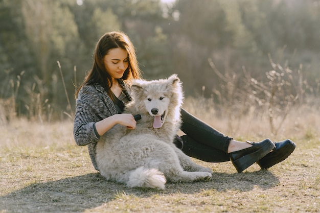 Foto gratuita ragazza alla moda in un campo soleggiato con un cane