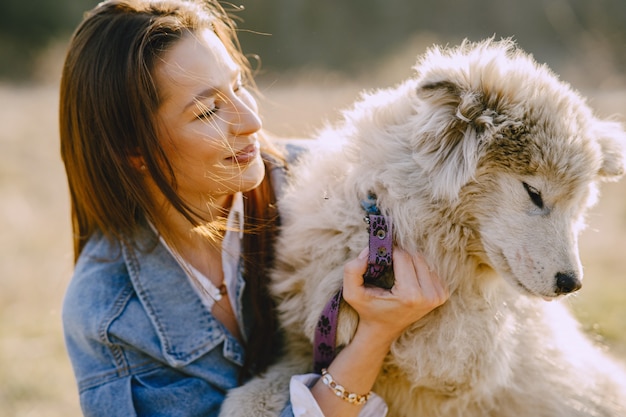 Stylish girl in a sunny field with a dog