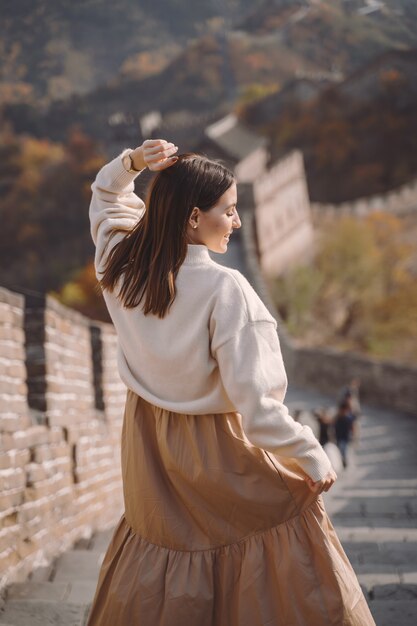 Stylish girl visiting the Great Wall of China near Beijing during autumn season.