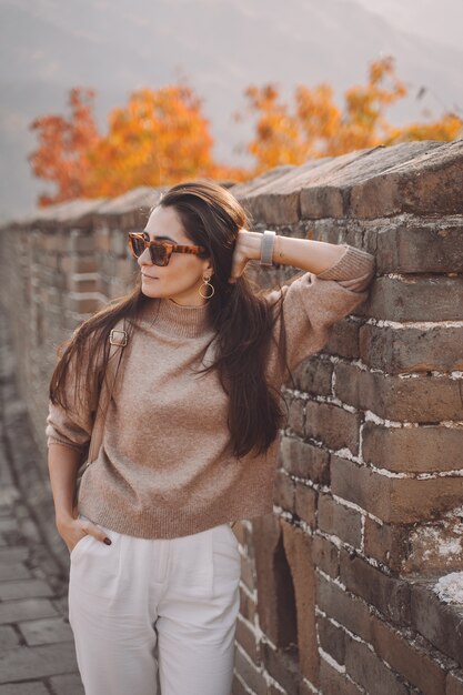 Stylish girl wearing sunglasses visiting the Great Wall of China