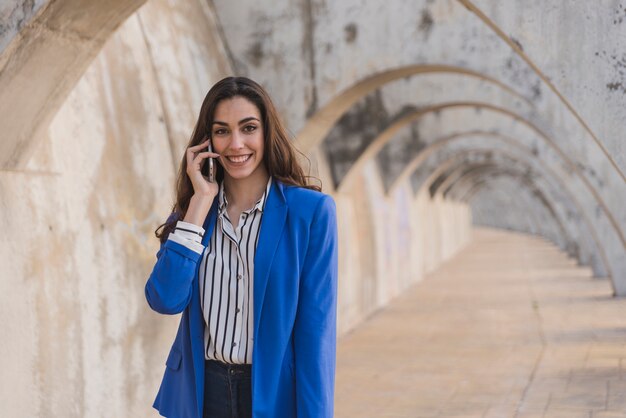 Ragazza alla moda con la giacca blu, parlando al telefono